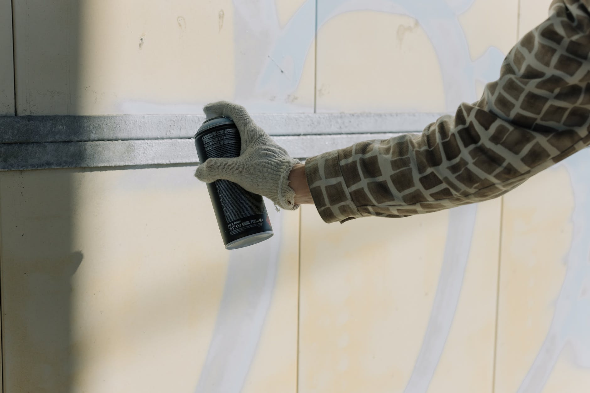 a person s hand wearing gloves spraying paint on the wall